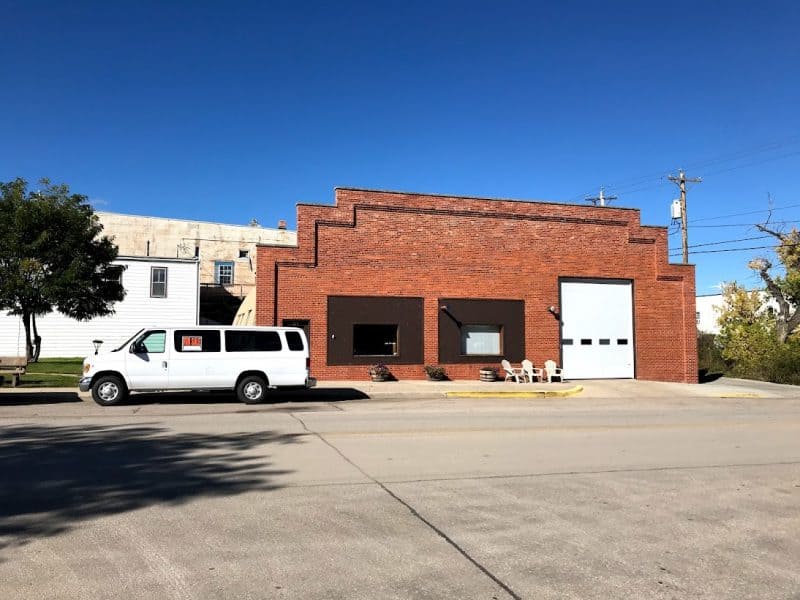 A clean and well maintained building with lawn chairs used as a break area. It's a business warehouse but there is no sign. 