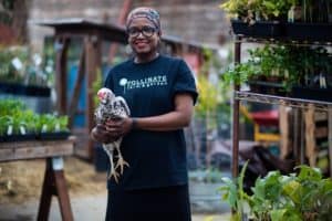 A woman holding a chicken in a garden