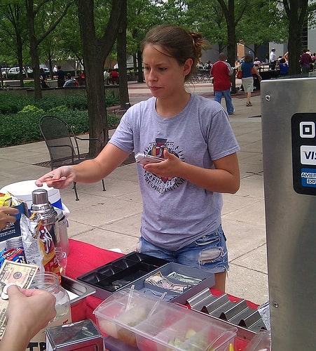 Mobile hot dog vendor accepts a credit card payment with a Square reader. 