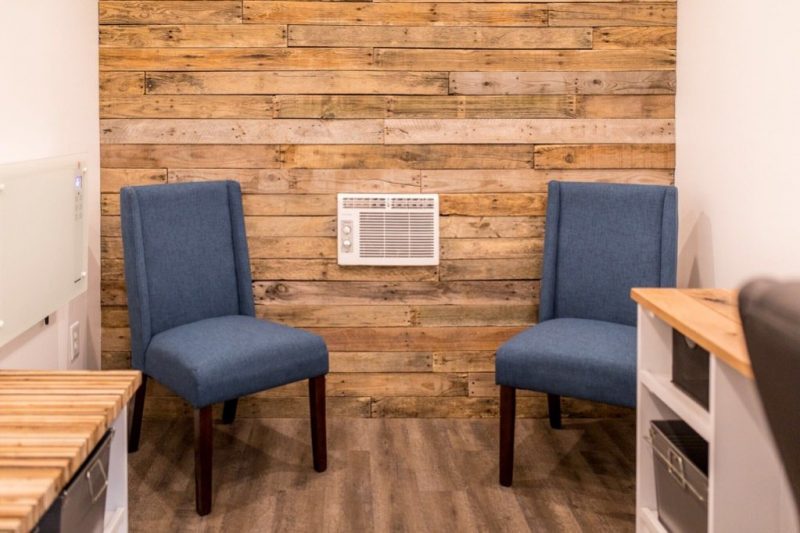 Two side chairs in the tiny office, in front of an all-wood paneled wall. 