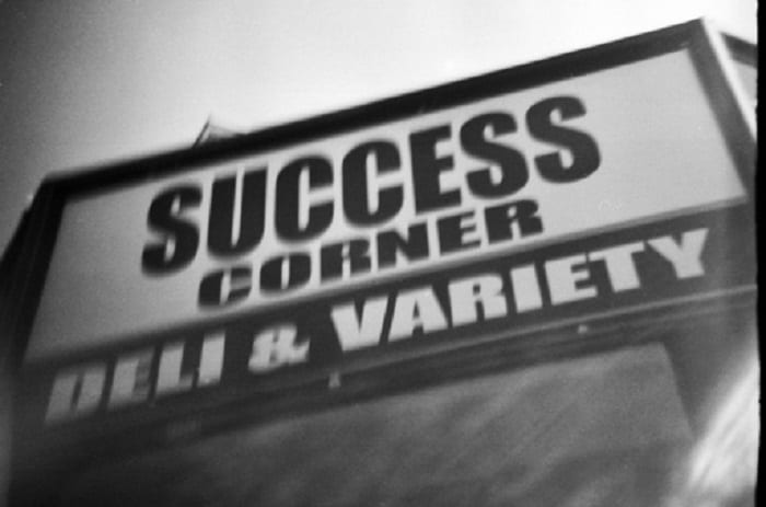 Sign says, "Success Corner Deli and Variety." 