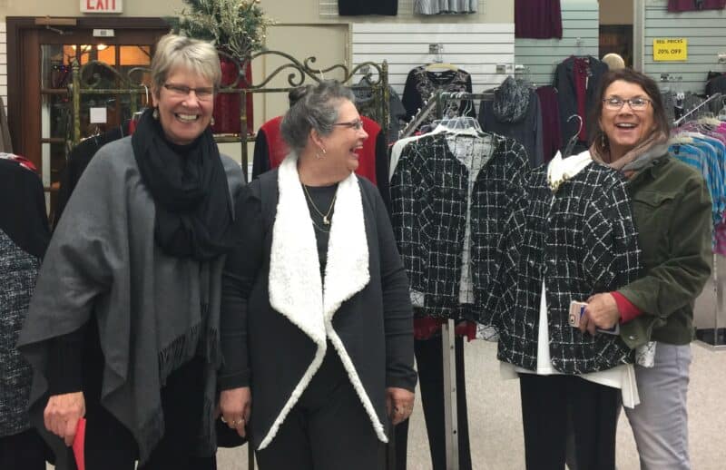 Three happy women stop and smile in a clothing store. 