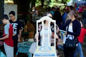 A woman carries an up-cycled chair she bought at Junque Fest surrounded by a diverse crowd